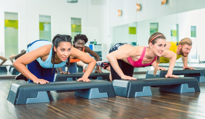 Determined women exercising push-ups on aerobic stepper platform